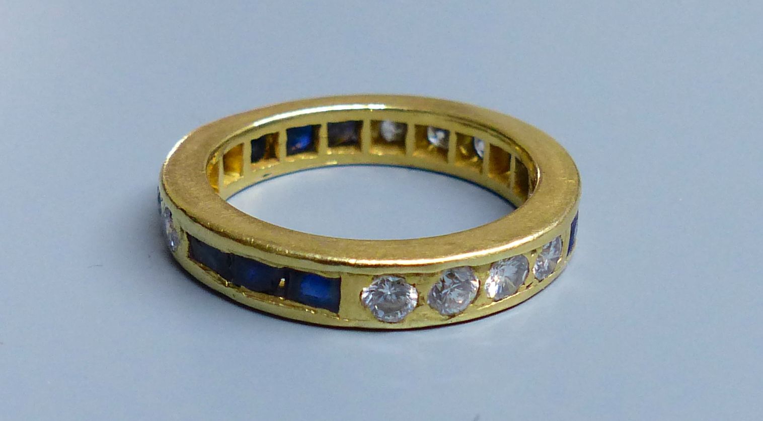 A modern yellow metal (tests as 18ct), sapphire and diamond set full eternity ring, size 0, gross 6.3 grams.